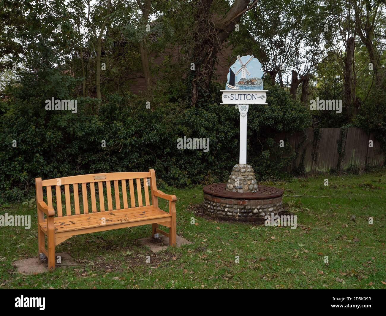 Traditional village sign with wooden bench at Sutton, Norfolk, UK Stock Photo