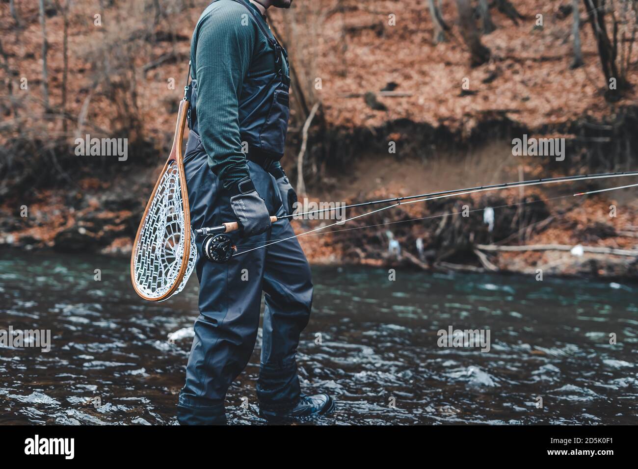 Fisherman fly fishing in river with rod, reel and landing net Stock Photo