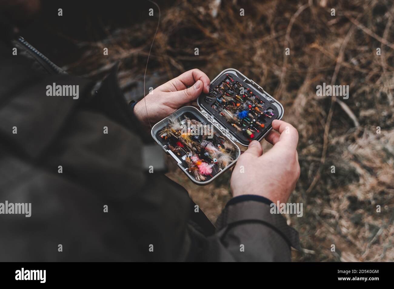Fisherman holding fly fishing lures box in hands. Stock Photo