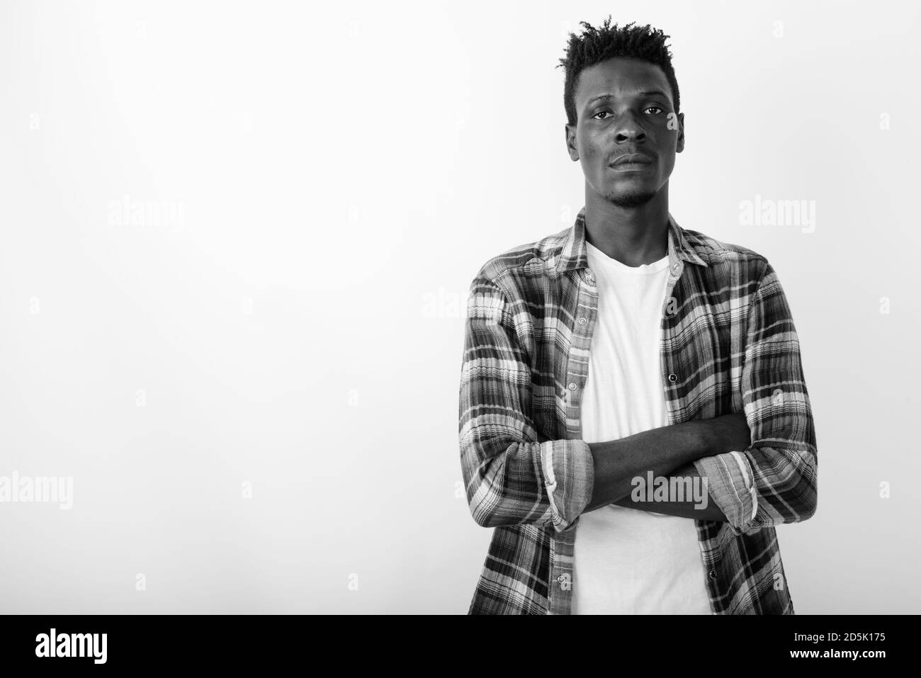 Studio shot of young black African man with arms crossed against white ...
