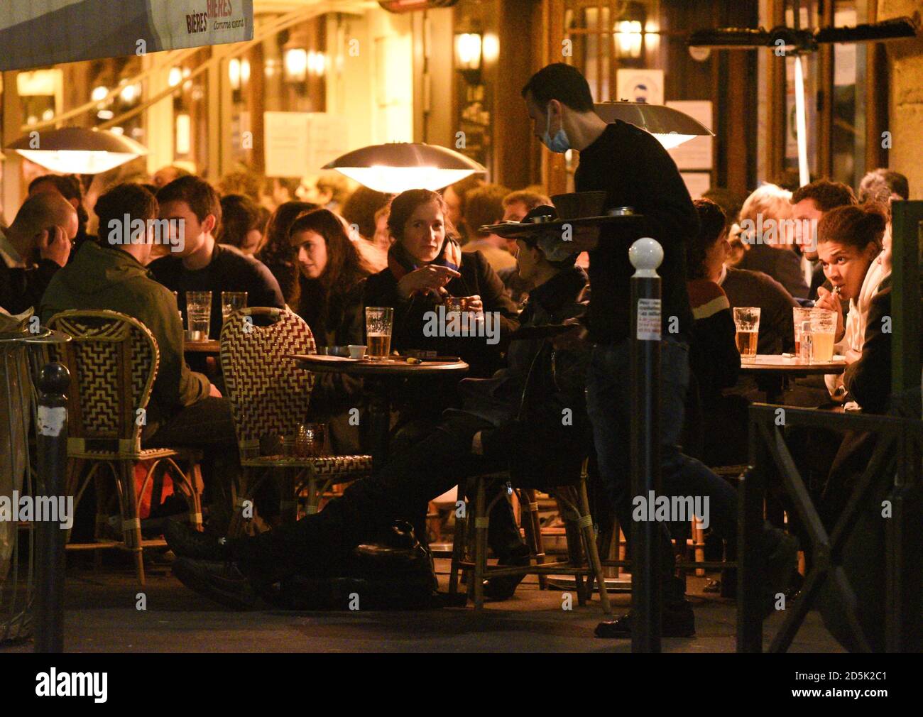 *** STRICTLY NO SALES TO FRENCH MEDIA OR PUBLISHERS - RIGHTS RESERVED ***October 13, 2020 - Paris, France: People sit and drink at bar and cafe terraces near Mouffetard street. Paris' bars were supposed to shut for two weeks after the French capital was placed on 'maximum Covid alert 'on October 5, with only restaurants staying open under strict guidelines. Several bars and cafes decided to stay open nonetheless, often serving potato chips or olives to ignore around the new regulation. The government is reportedly mulling a stricter curfew to limit the spread of the coronavirus. Stock Photo