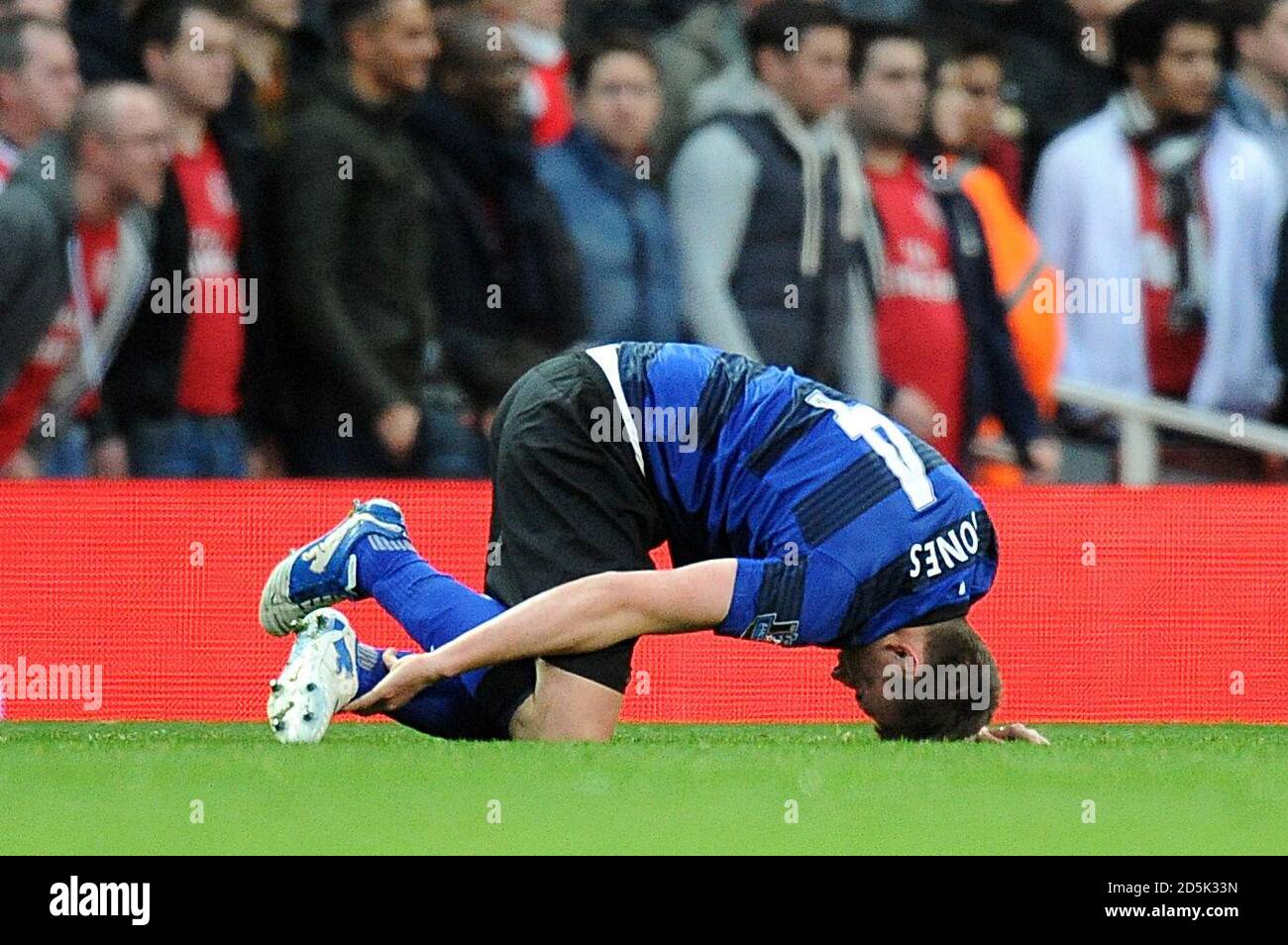 Manchester United's Phil Jones holds his ankle as he lies injured on the pitch before being substituted off  Stock Photo