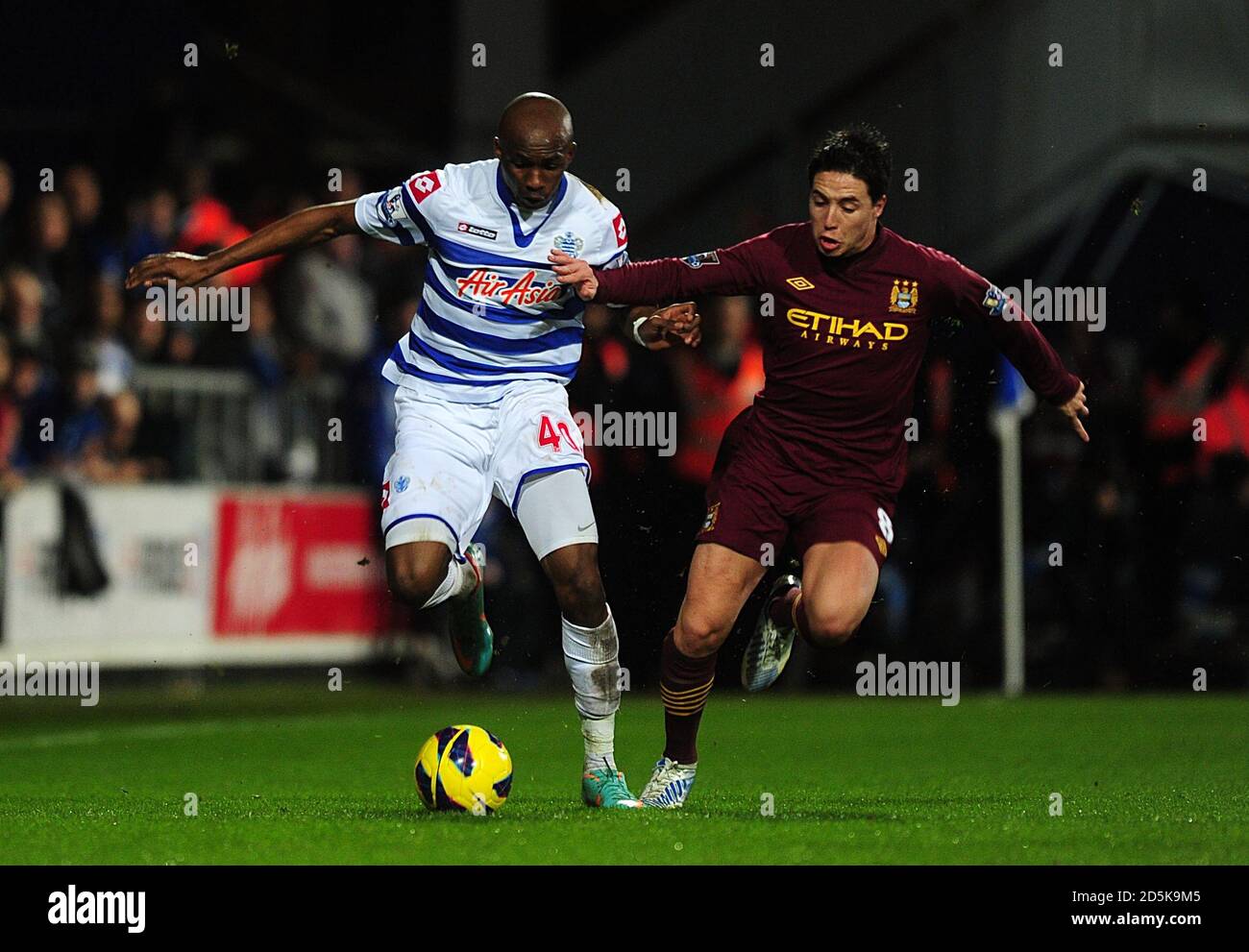 Queens Park Rangers' Stephane M'Bia (left) and Manchester City's Samir Nasri battle for the ball Stock Photo