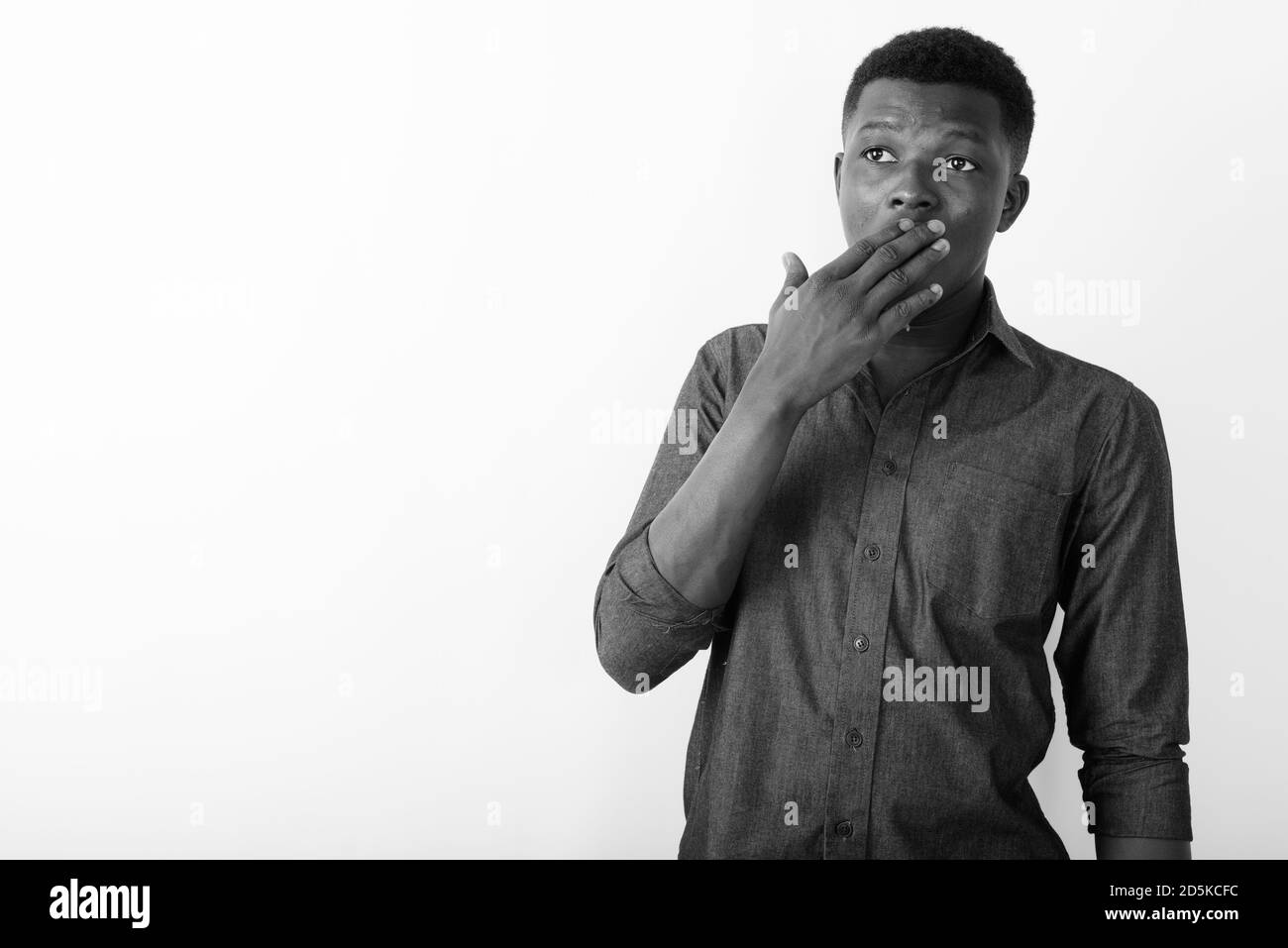 Studio shot of young black African man thinking and looking shocked ...