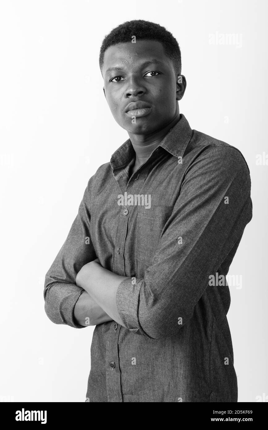 Studio shot of young black African man with arms crossed against white ...