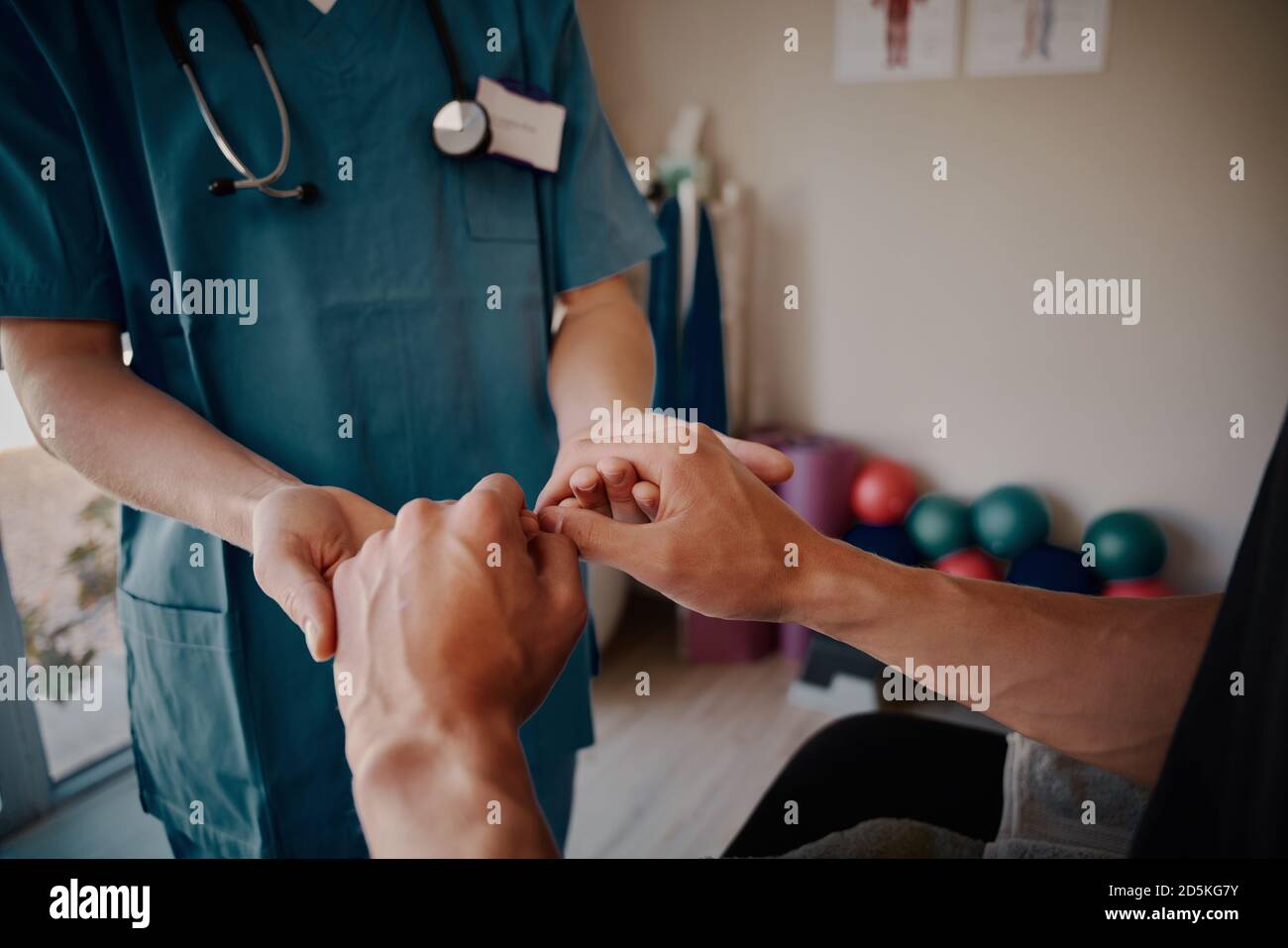 Closeup of young woman nurse holding male patients hands in hospital Stock Photo