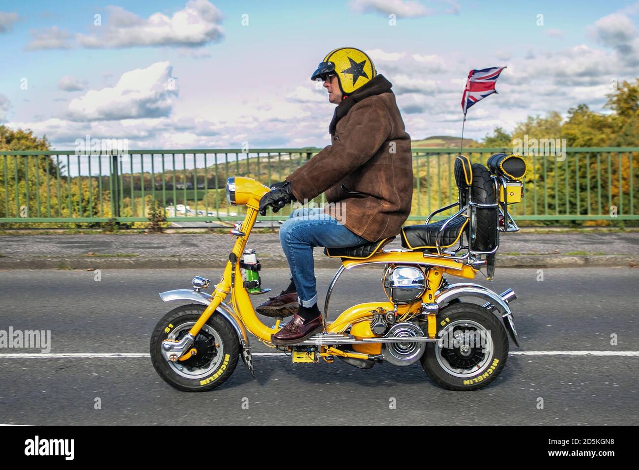 Yellow small retro mini scooter Motorbike rider; two wheeled transport, motorcycles, vehicle, roads, motorbikes, bike riders motoring in Chorley, UK Stock Photo