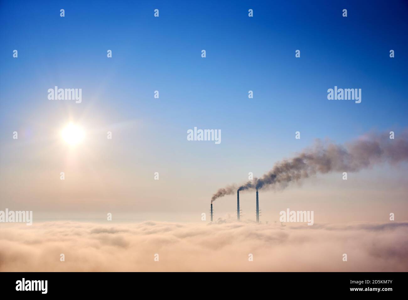 Tops of three smoking stacks of thermal power station on the horizon