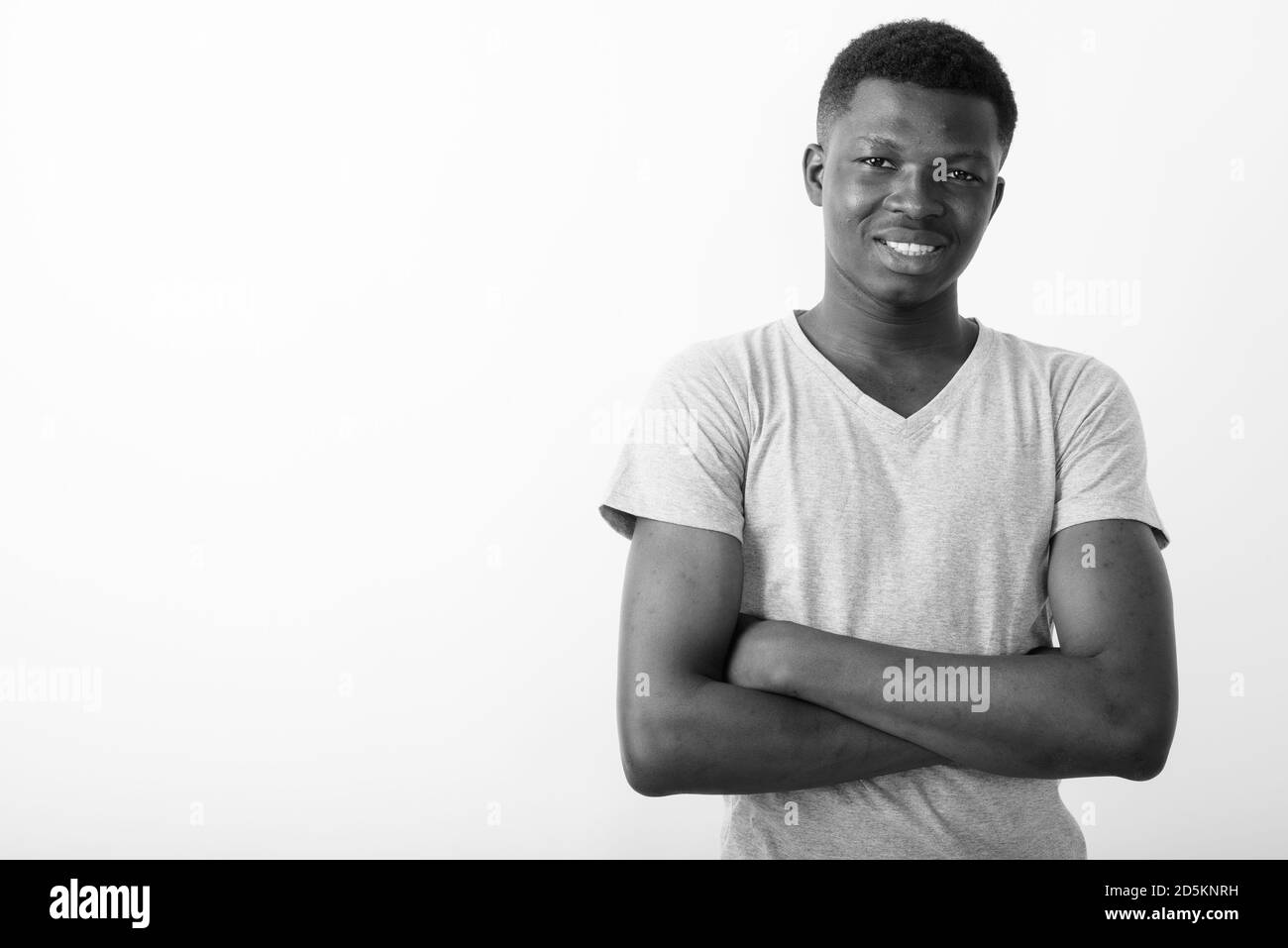 Studio shot of young happy black African man smiling with arms crossed ...