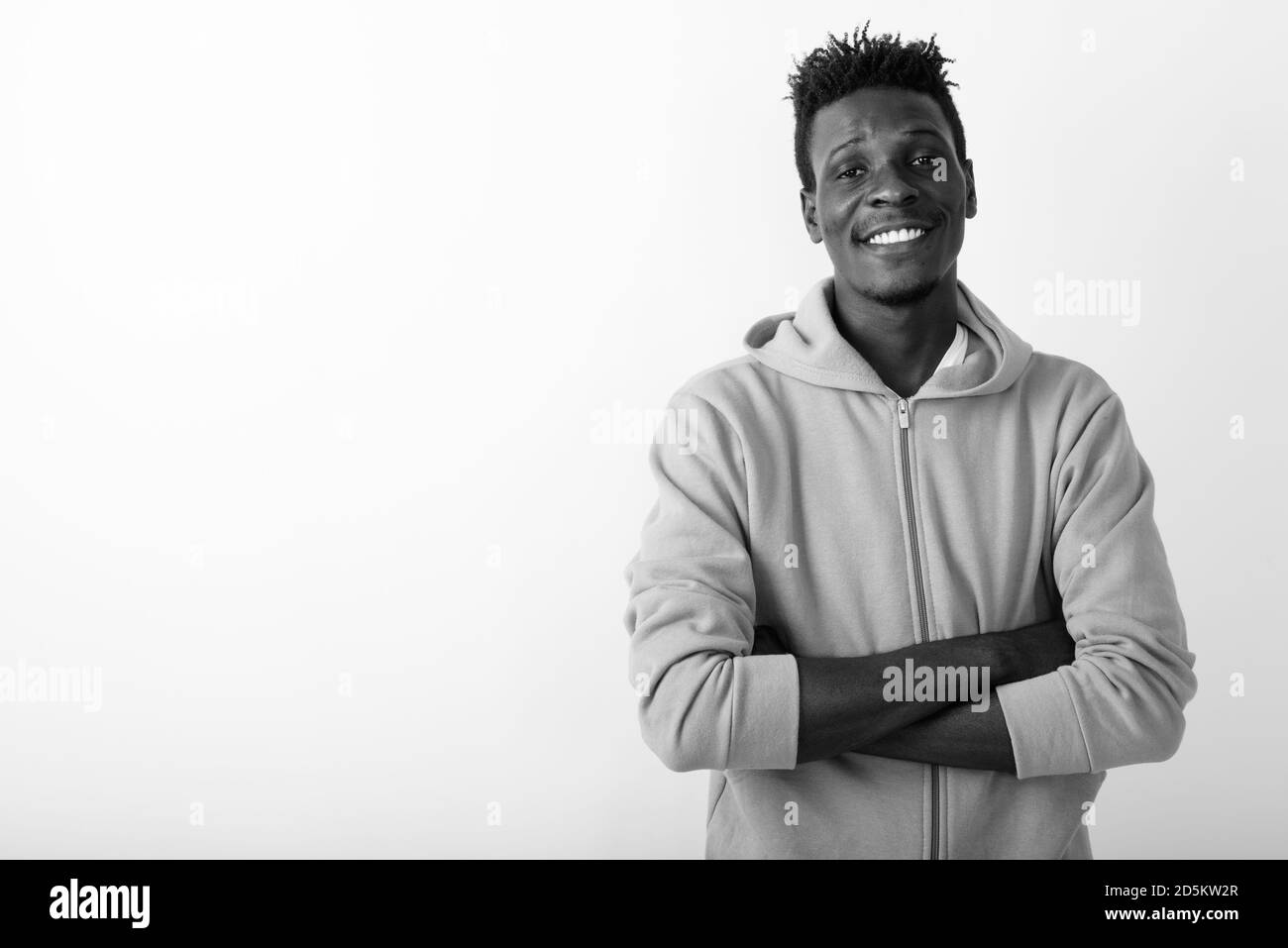 Studio shot of young happy black African man smiling with arms crossed ...