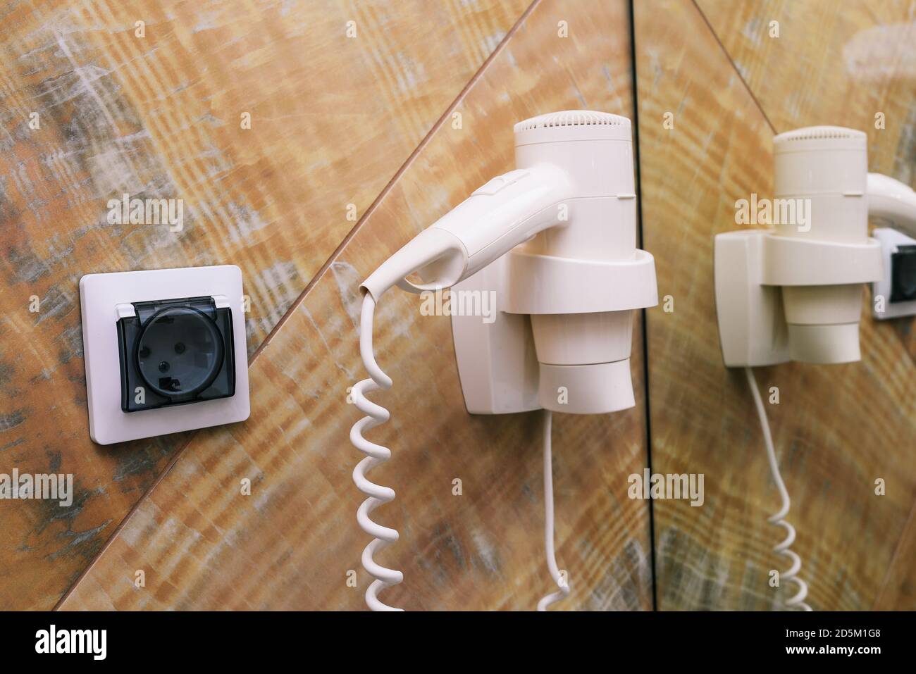Hair dryer on the wall with socket and mirror. Electric hair dryer in the  bathroom Stock Photo - Alamy