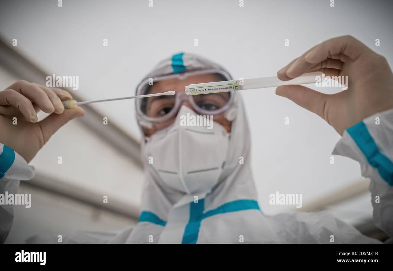 Berlin, Germany. 14th Oct, 2020. A member of the medical staff inserts a cotton swab into a tube after a PCR smear to test for Covid-19. In the corona test centre at the Ärztehaus Mitte, citizens without corona symptoms can be tested in a tent in the car park in front of the doctor's practice in order to be able to present a test result that is as negative as possible, for example for a trip or for professional reasons. Credit: Michael Kappeler/dpa/Alamy Live News Stock Photo