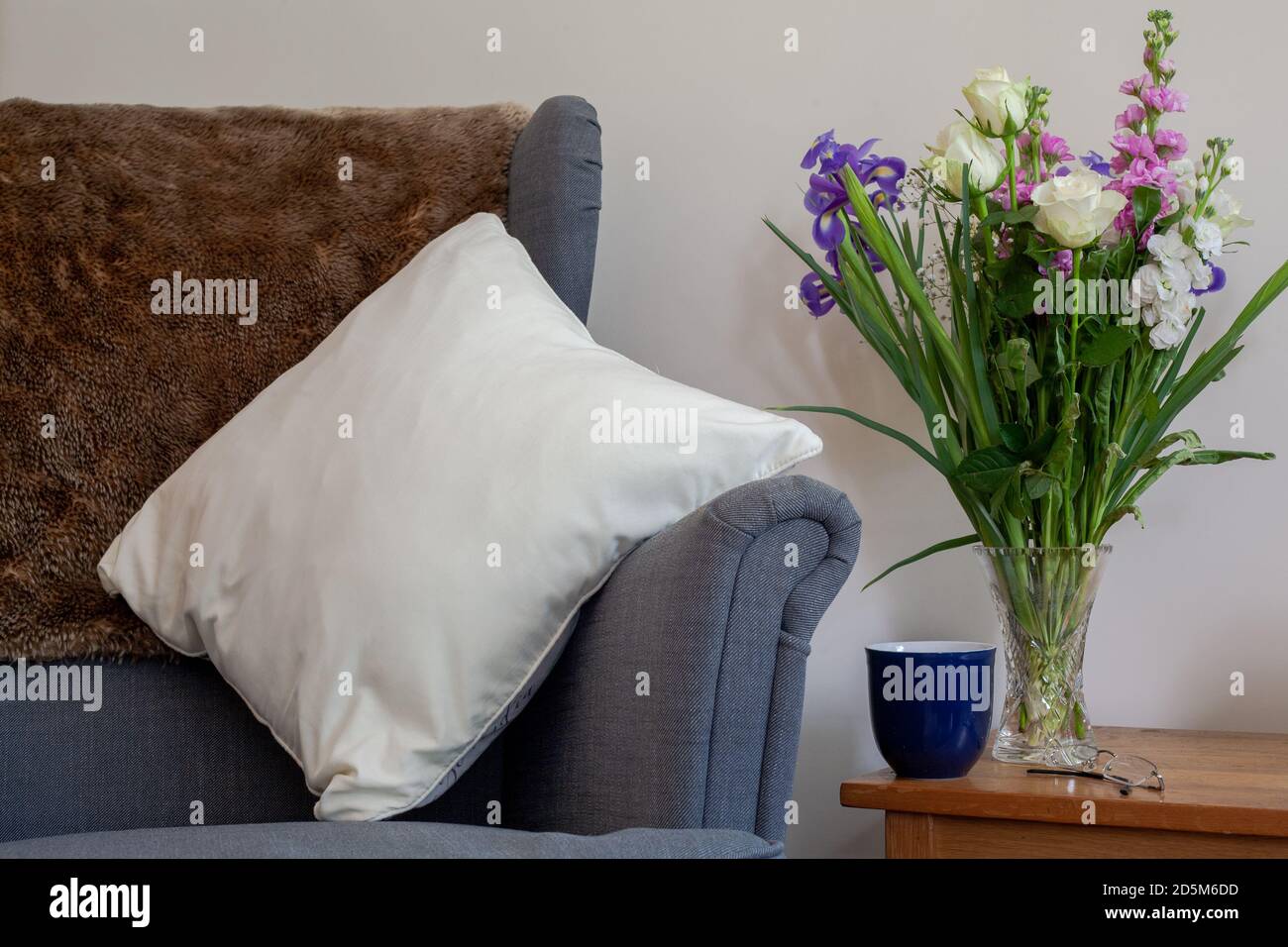 Cozy reading indoor space with vase of flowers. Staying home indoors space reading. Stock Photo