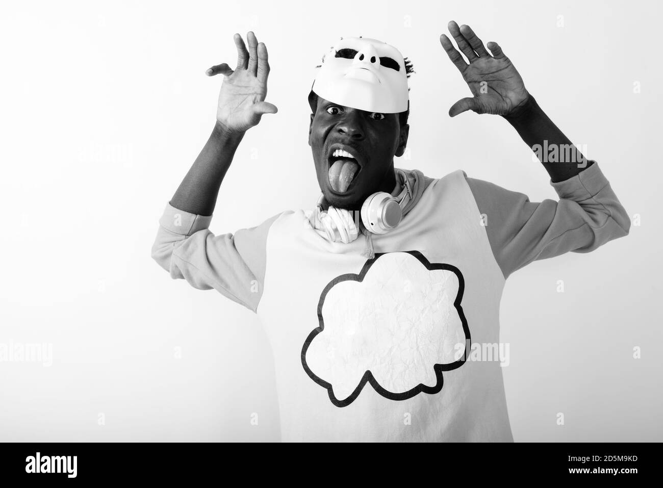 Studio shot of young black African man sticking tongue out while wearing white mask on top of head Stock Photo