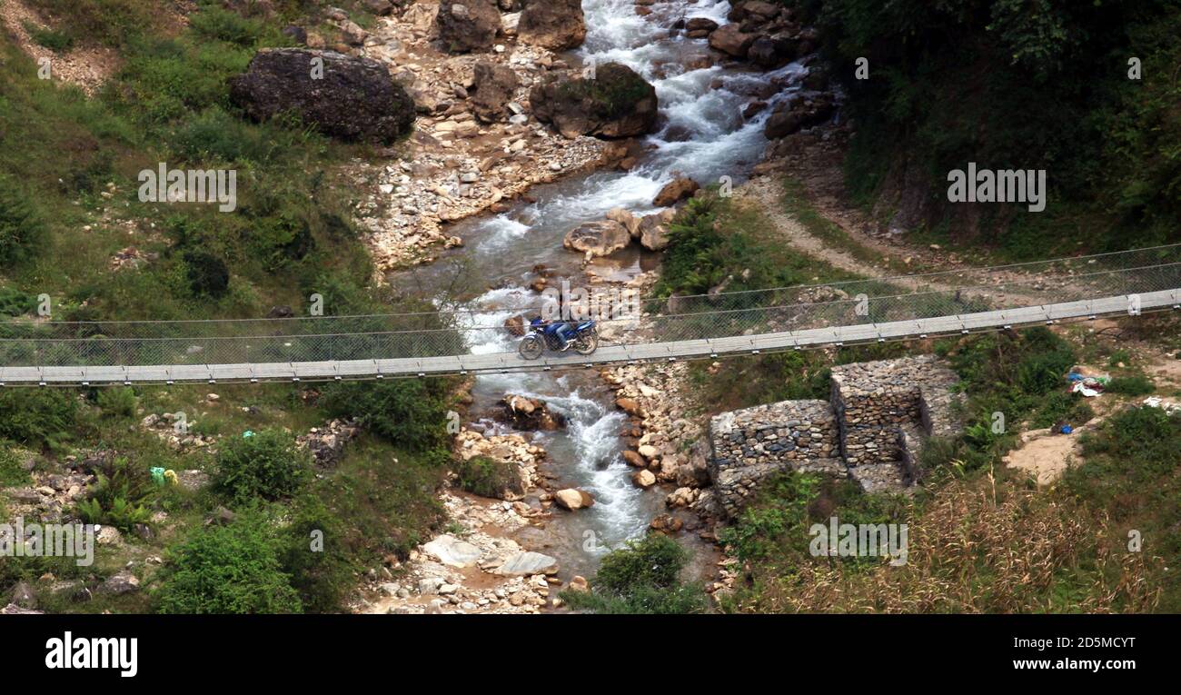 Rolpa, Nepal. 14th Oct, 2020. A man rides a motorcycle on a suspension bridge at a village in Rolpa, western Nepal on October 14, 2020. Credit: Sunil Sharma/ZUMA Wire/Alamy Live News Stock Photo