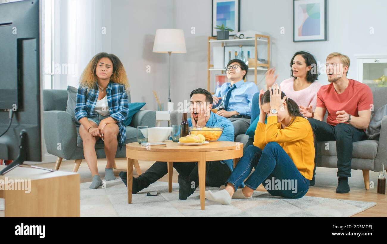 In the Living Room Diverse Group of Friends on Watching Sports Game Match on TV, They Cheer and Chant for the Team, But are Disappointed after Team Stock Photo