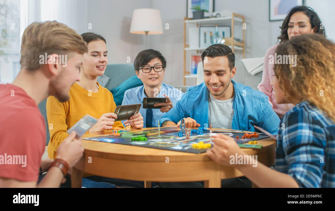 Diverse Group of Guys and Girls Playing in a Strategic Board Game with  Cards and Dice. Cozy Living Room in a Daytime Stock Photo - Alamy
