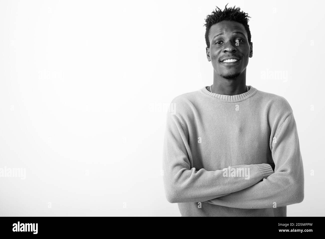 Studio shot of young happy black African man smiling with arms crossed ...