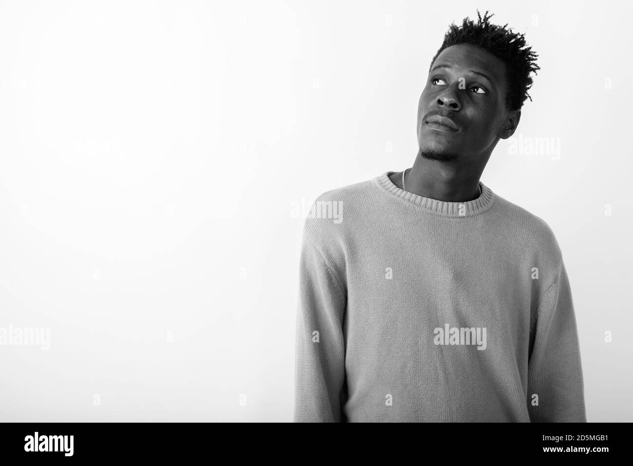 Studio shot of young black African man thinking while looking up ...