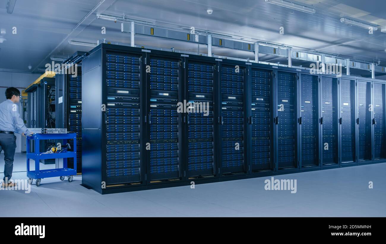 In the Modern Data Center: Team of IT Technicians Working with Server Racks, Running Maintenance and Diagnostics, Checking Networking and Cloud Stock Photo