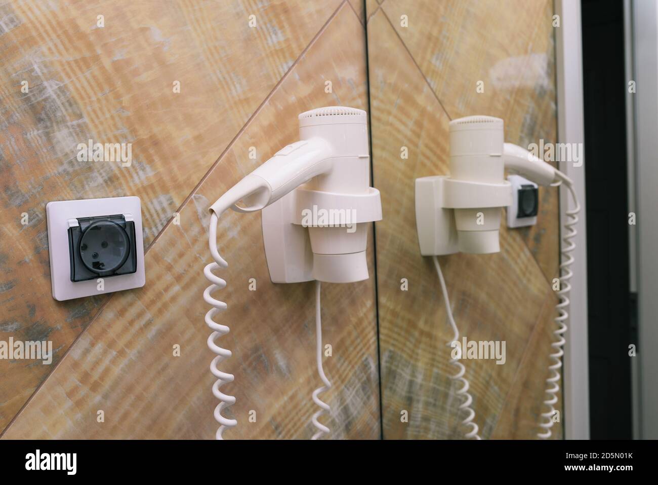 Hair dryer on the wall with socket and mirror. Electric hair dryer in