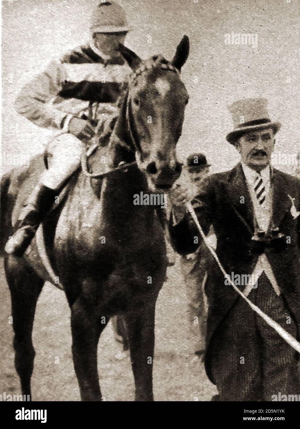 1932  Tom Walls, the then popular actor, horse owner and trainer, leading his horse April the Fifth after winning the English Derby. Thomas Kirby Walls (1883 – 1949) was an English stage and film actor, producer and director, best known for presenting and co-starring in the Aldwych farces in the 1920s and for starring in and directing their film adaptations.He set up stables at his home in Surrey and succesfully trained around  150 winners, including April the Fifth, his 1932 Derby winner.  April the 5th was a British Thoroughbred racehorse and sire. Jockey is Fred (Frederick) Lane. Stock Photo