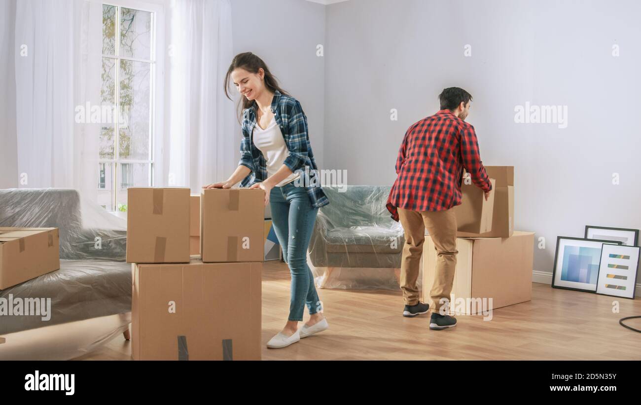 Happy Young Couple Moving in Into New Apartment, Carrying Cardboard
