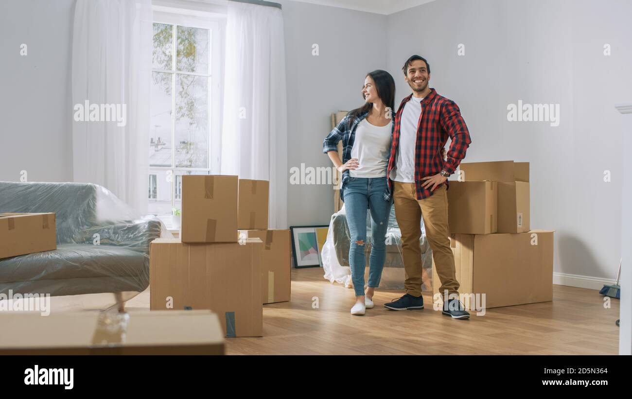 Happy Young Couple Moving Into New Apartment, Carrying Cardboard Boxes ...