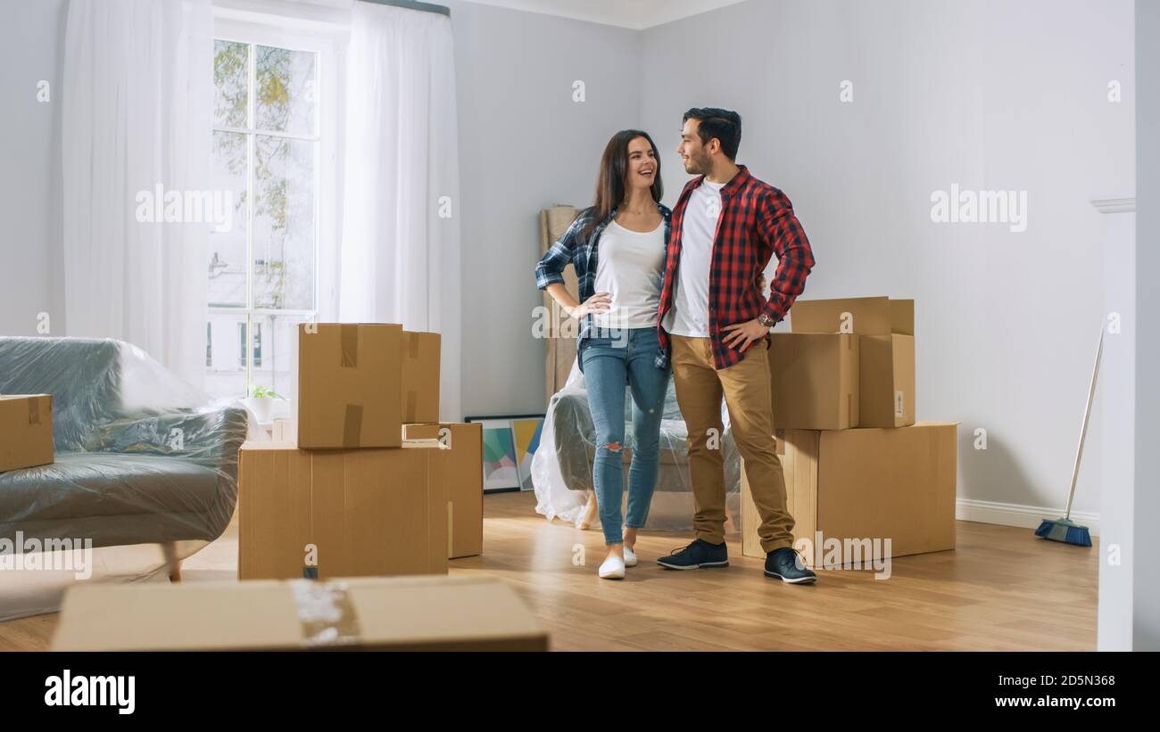 Happy Young Couple Moving Into New Apartment, Carrying Cardboard Boxes ...