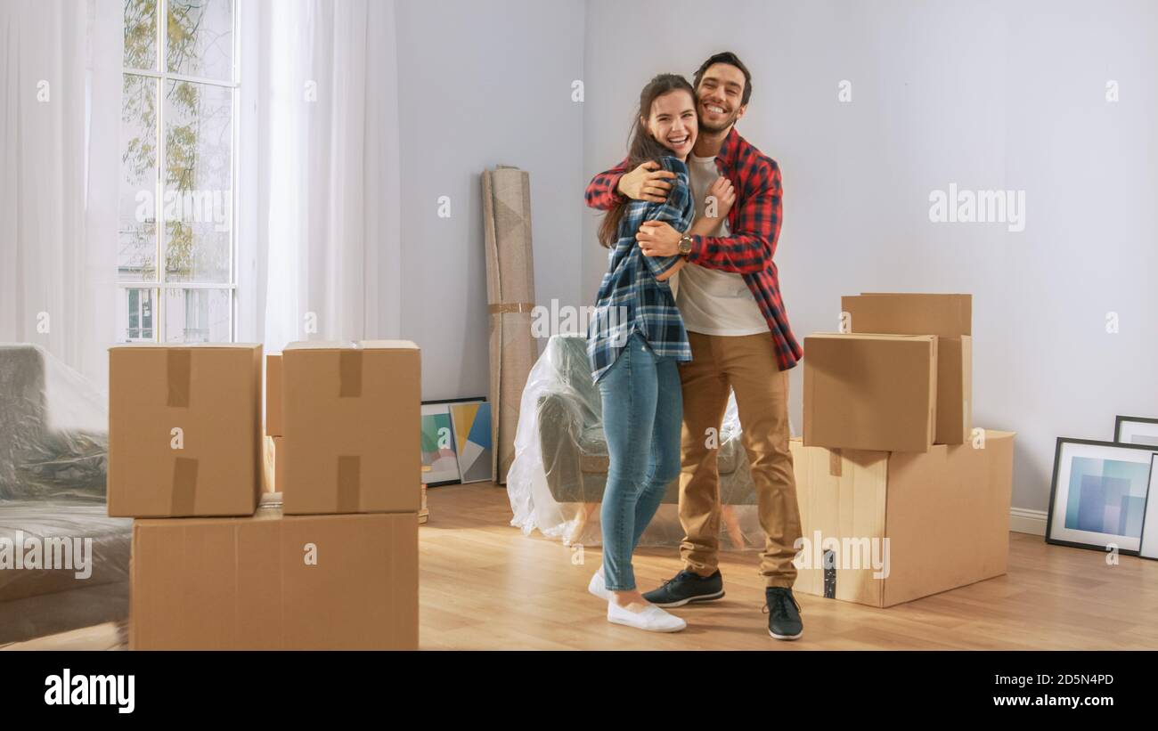 Happy Young Couple Moving Into New Apartment, Carrying Cardboard Boxes ...
