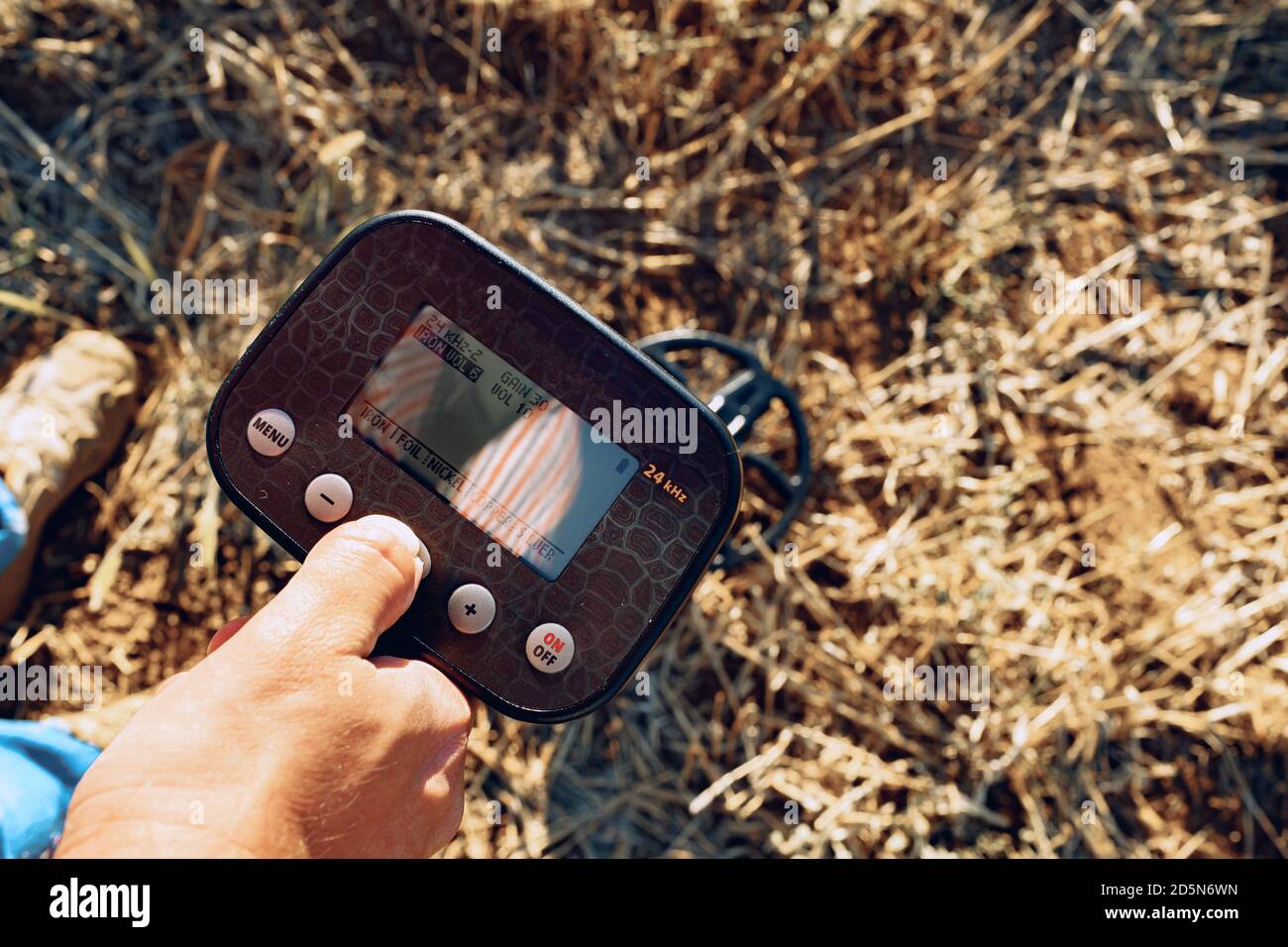 Male hand holding metal detector device above the ground Stock Photo ...