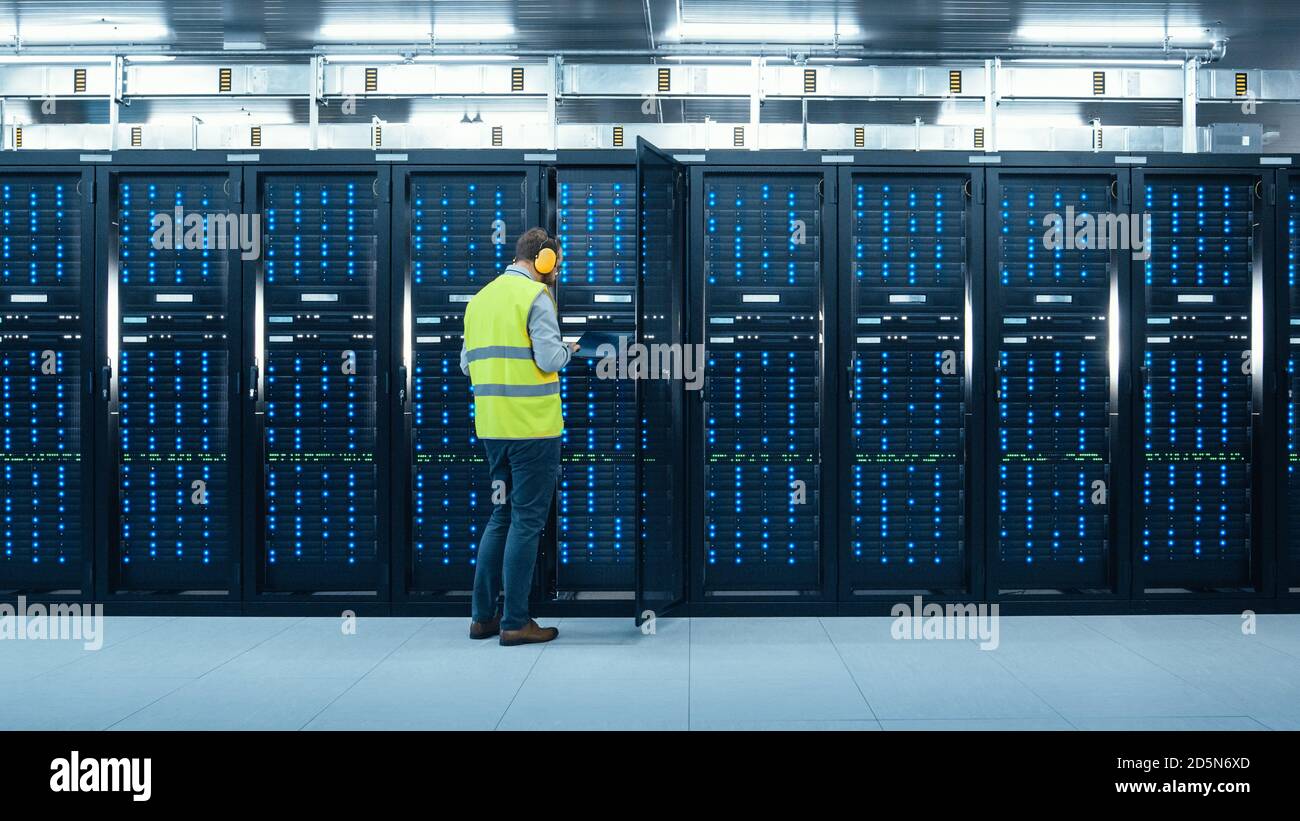 Shot of an IT Engineer in High Visibility Vest and Headphones Working ...