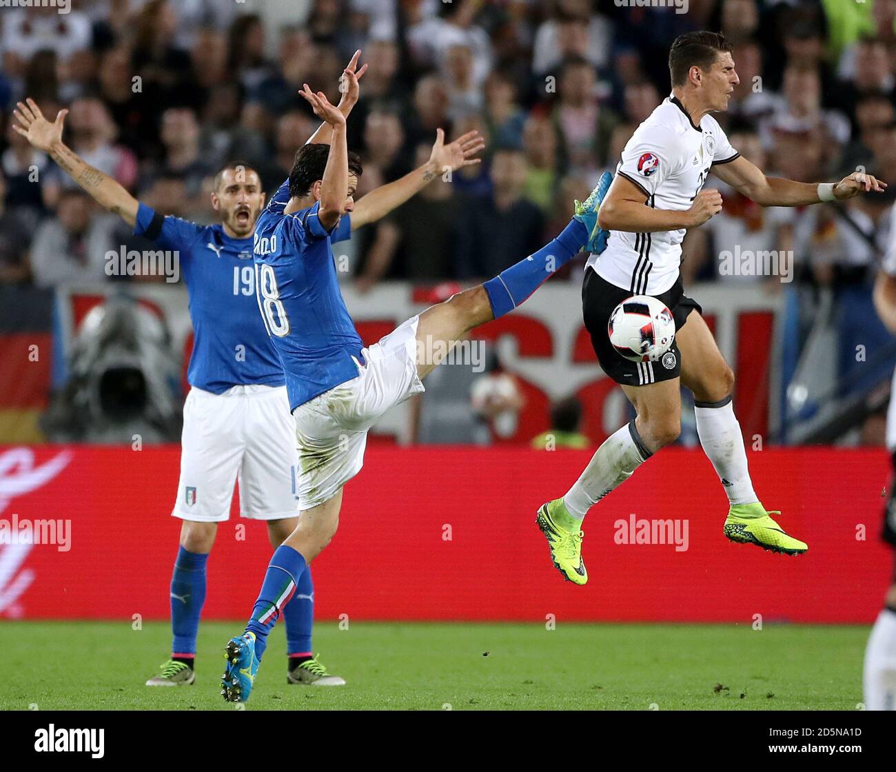 Italy's Marco Parolo (centre) and Germany's Mario Gomez (right) battle for the ball  Stock Photo