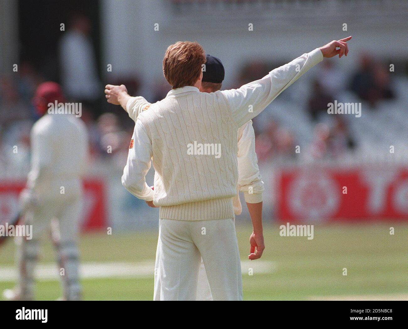 There seems to be a difference of opinion between England's captain Michael Atherton (hidden) and teammate Shaun Udal (front) about field placings  Stock Photo