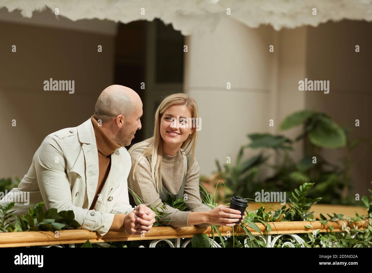 Smiling young woman talking to the man while they standing on the balcony Stock Photo