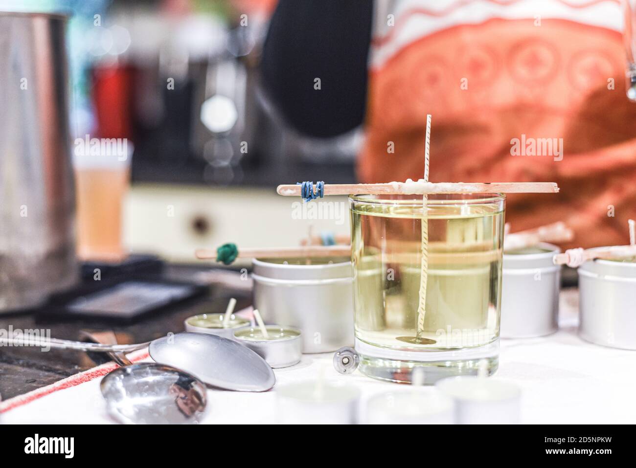 Making candles at home and adding a wick to liquid candle wax Stock