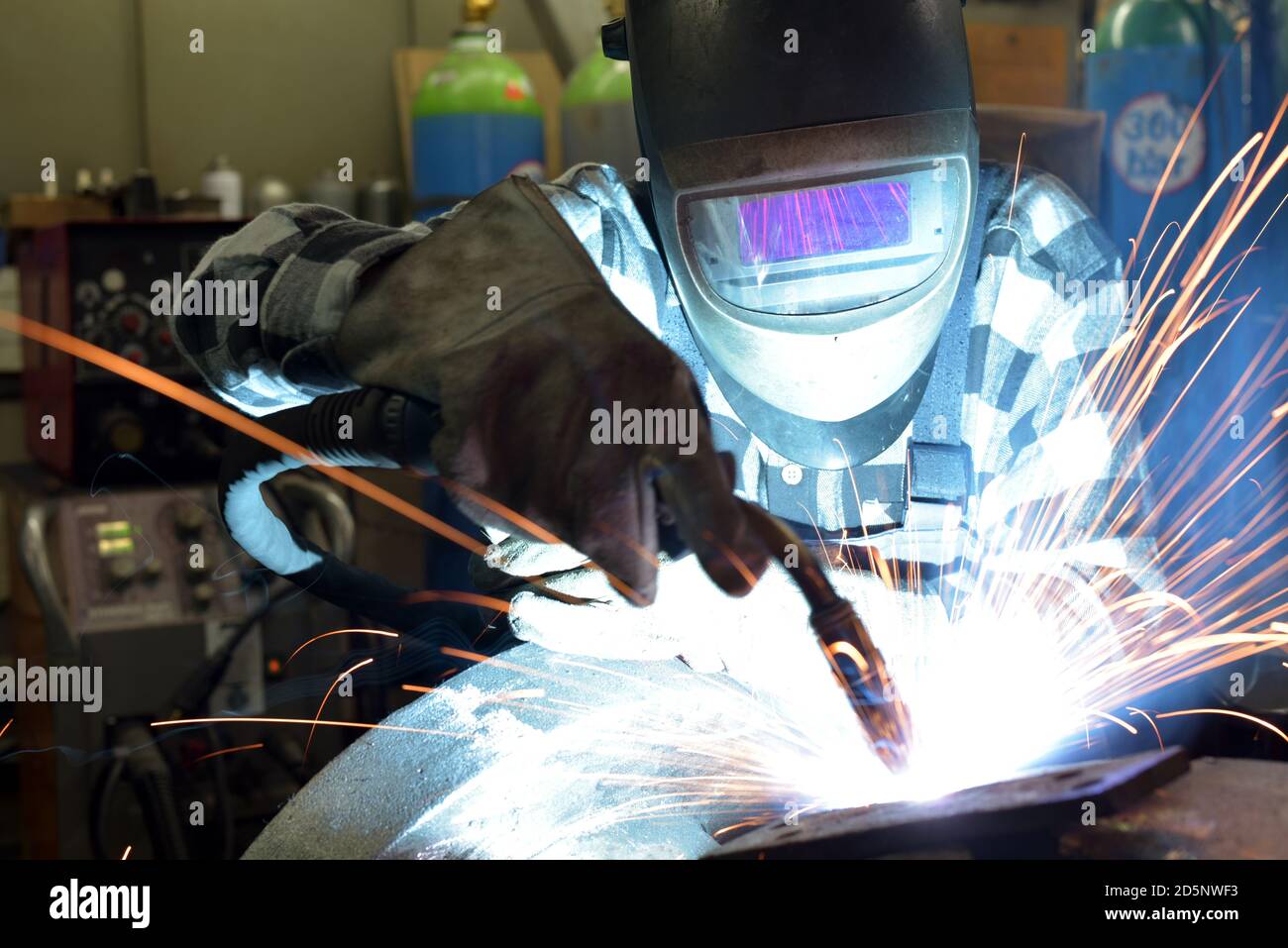 Welder in protective clothing at the workplace in an industrial company in steel construction Stock Photo