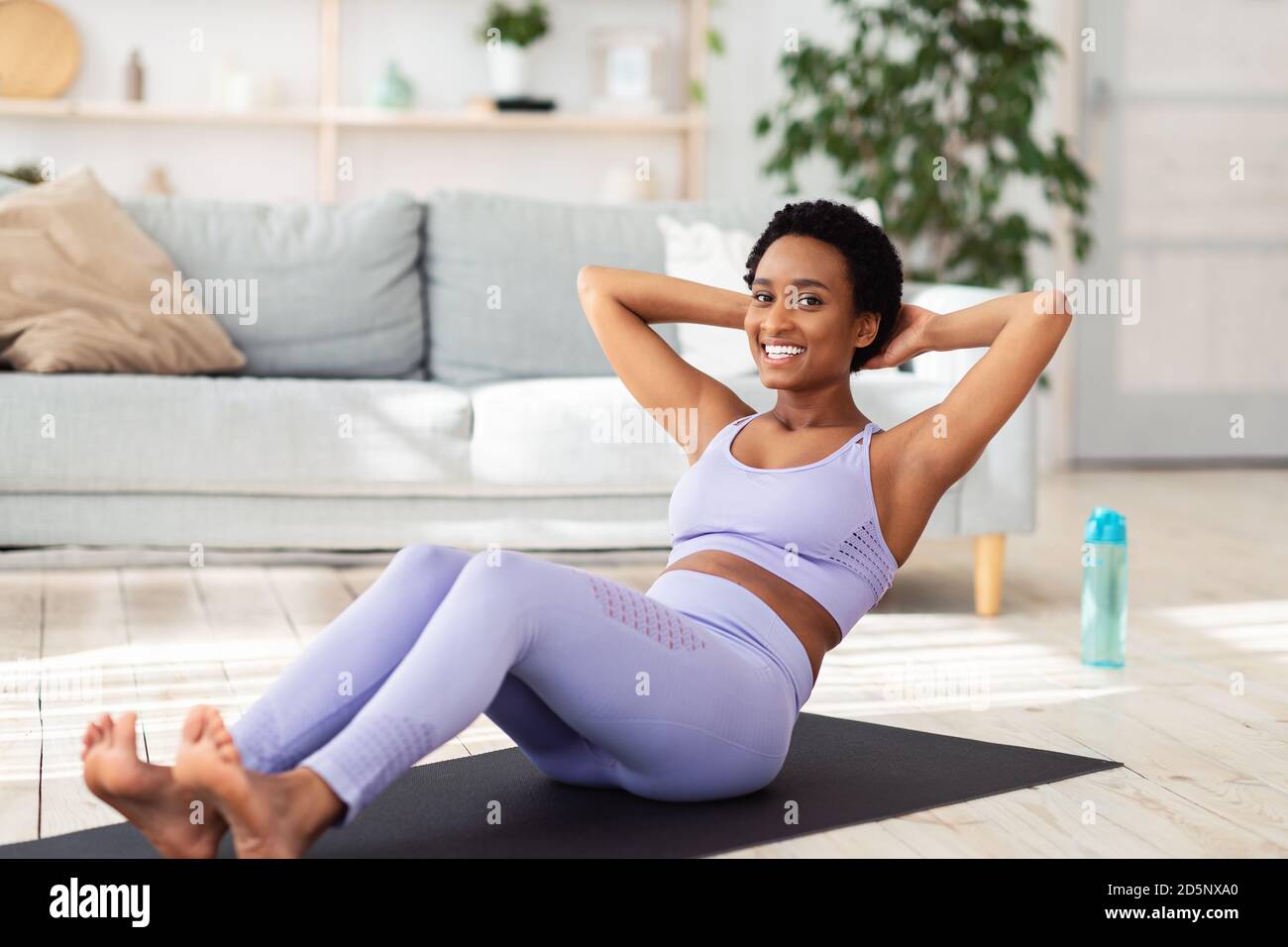 Positive athletic black woman doing abs exercises during her home