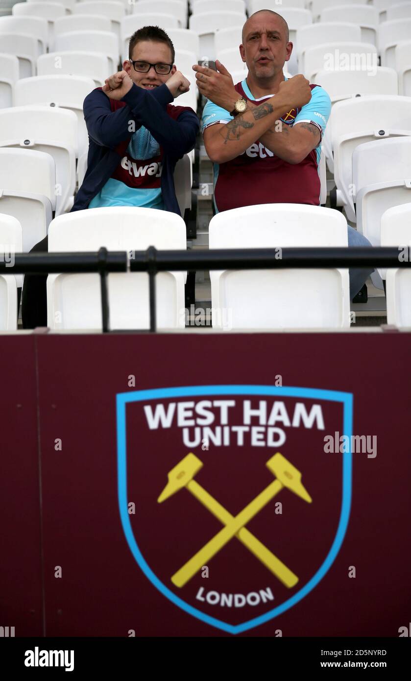 West Ham United fans in the stands make a cross hammer gesture Stock