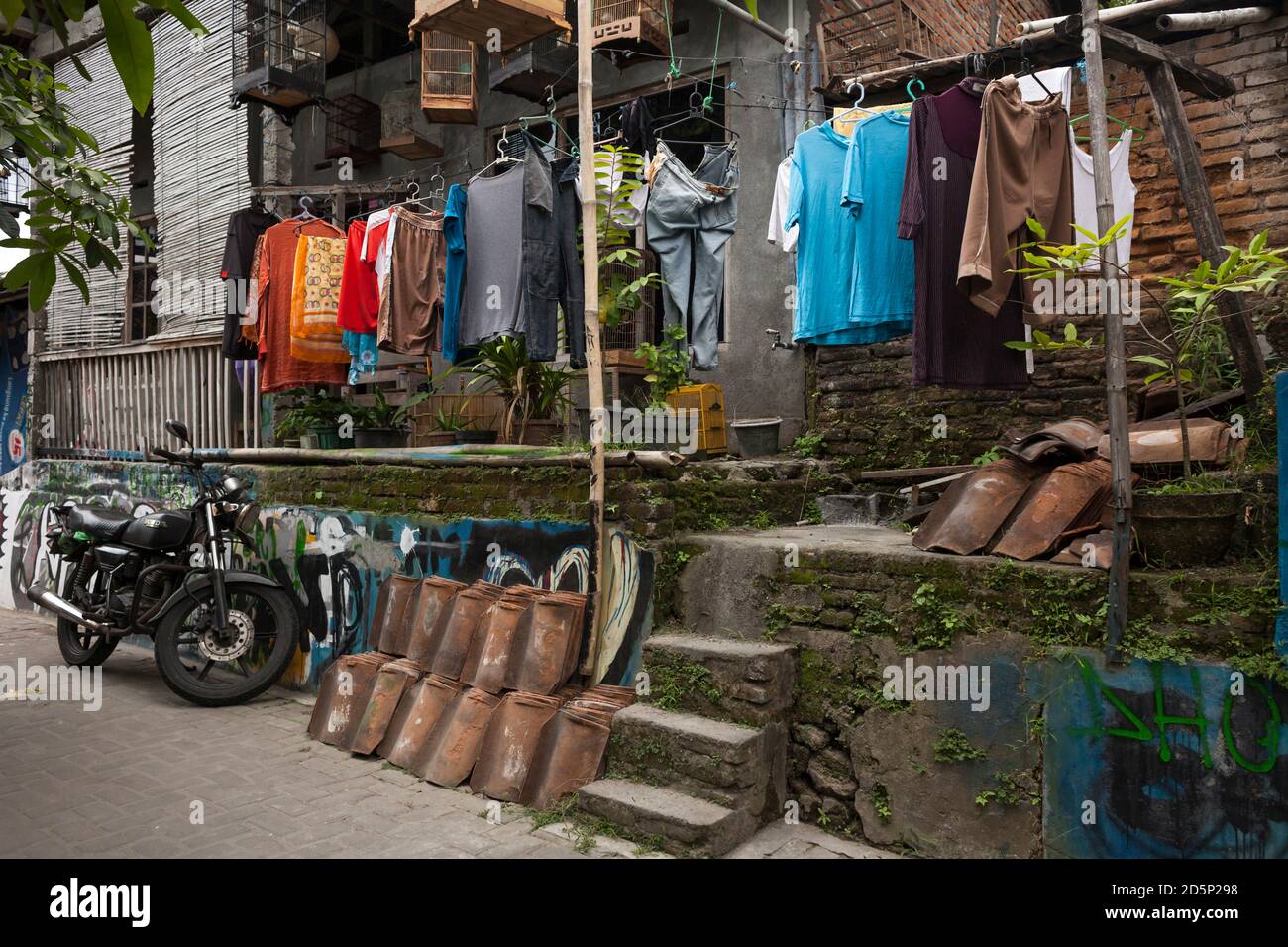 Horizontal shot of some piled tiles, cages and hanging clothes on a city center street, Yogyakarta, Java, Indonesia Stock Photo