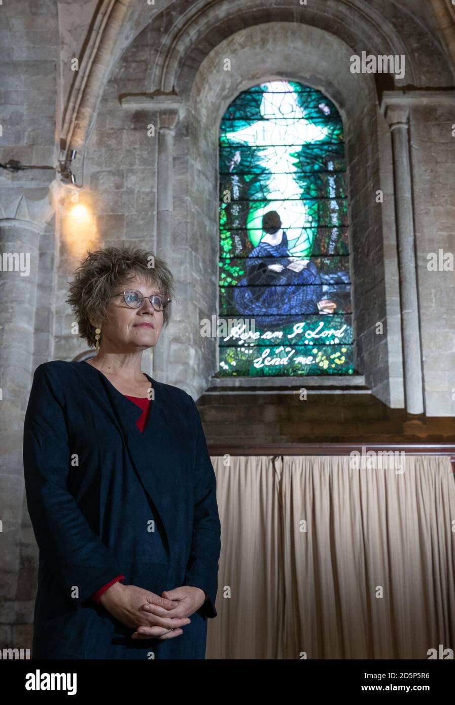 Artist Sophie Hacker stands in front of the newly installed stained glass window of Florence Nightingale, known as 'The Calling Window', in Romsey Abbey in Hampshire. The window, which has been installed to mark the bicentenary of her birth, depicts Florence seated on a stone bench in the grounds of her family home, Embley Park, and shows the moment when she said she was called to God aged 16. Stock Photo