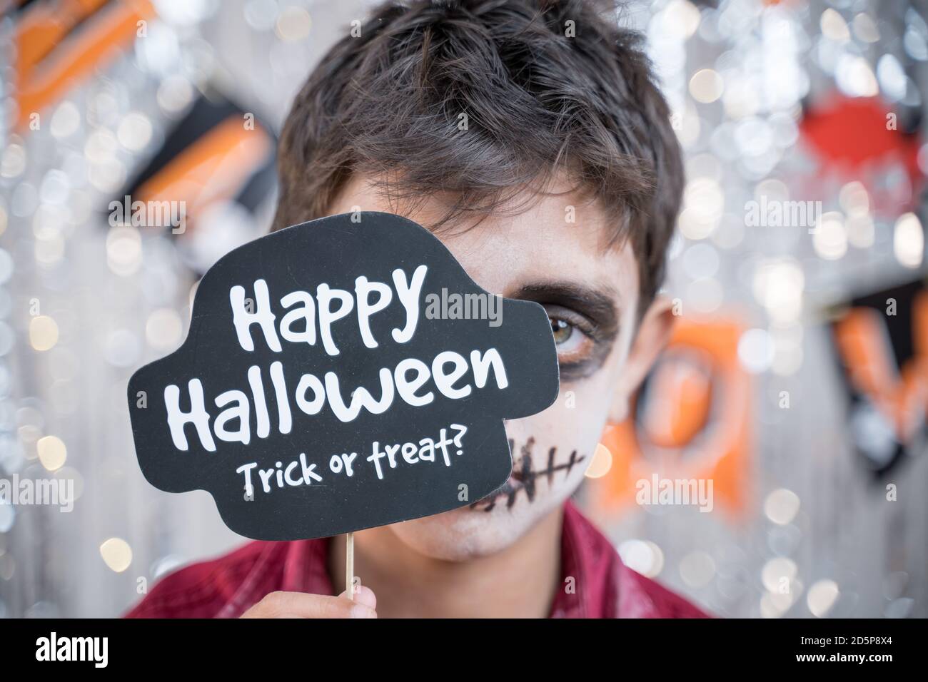 Kid hloding Halloween booth prop infront of spooky face - concept of halloween trick or treat. Stock Photo