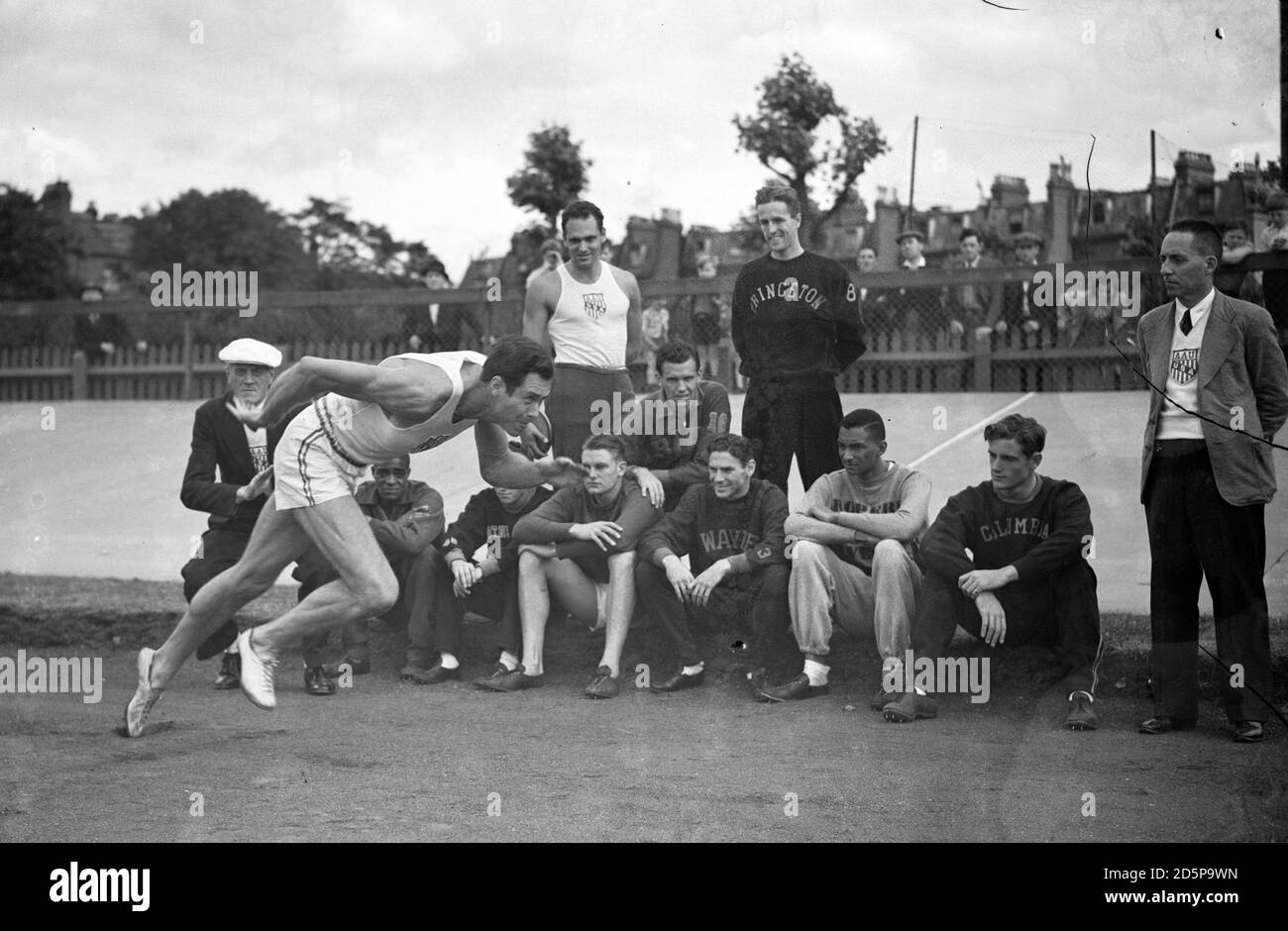 Perrin Walker, of Oglethorpe, Georgia, the 100 yards sprinter in action, is watched by his American team-mates at the White City Stadium, London. Stock Photo