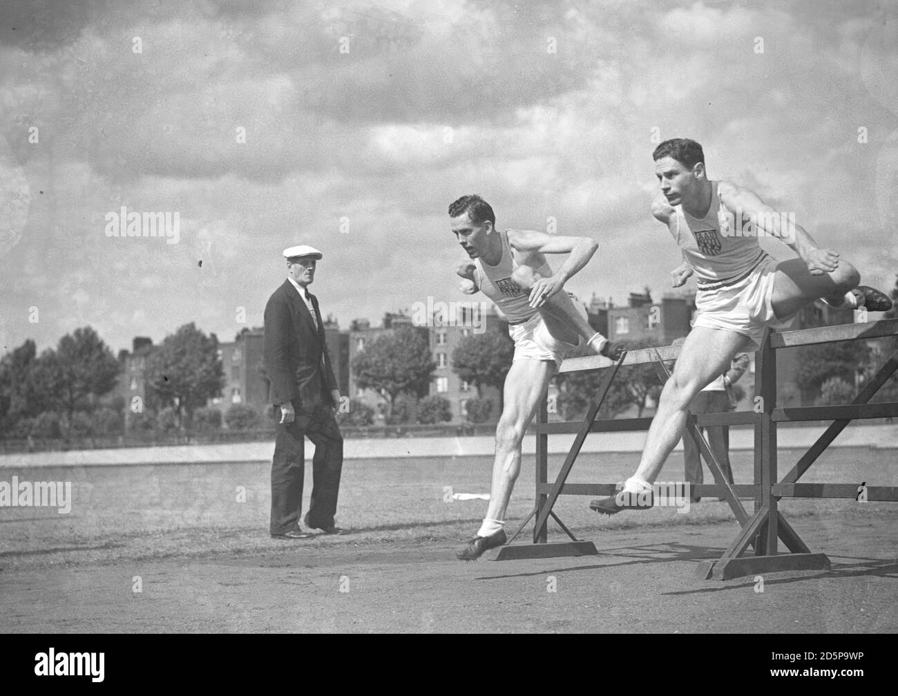 American team-mates Alan Tomlich (nearest) and Jack Patterson, the 220 yards hurdlers, practise at the White City Stadium, London, for the International Athletic Meeting. Stock Photo