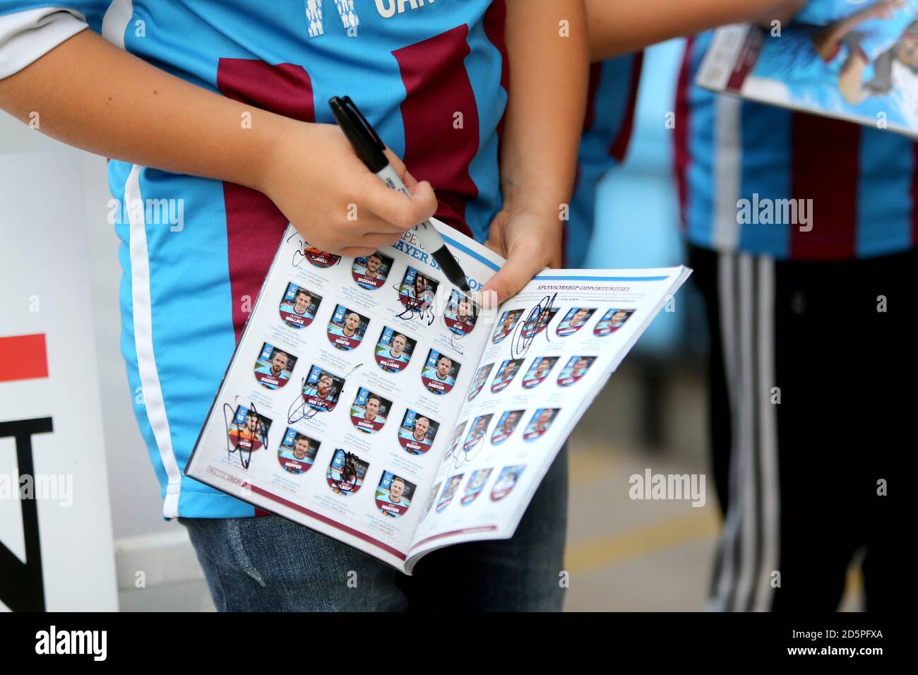 A Scunthorpe United fan collects autographs in his match day programme Stock Photo