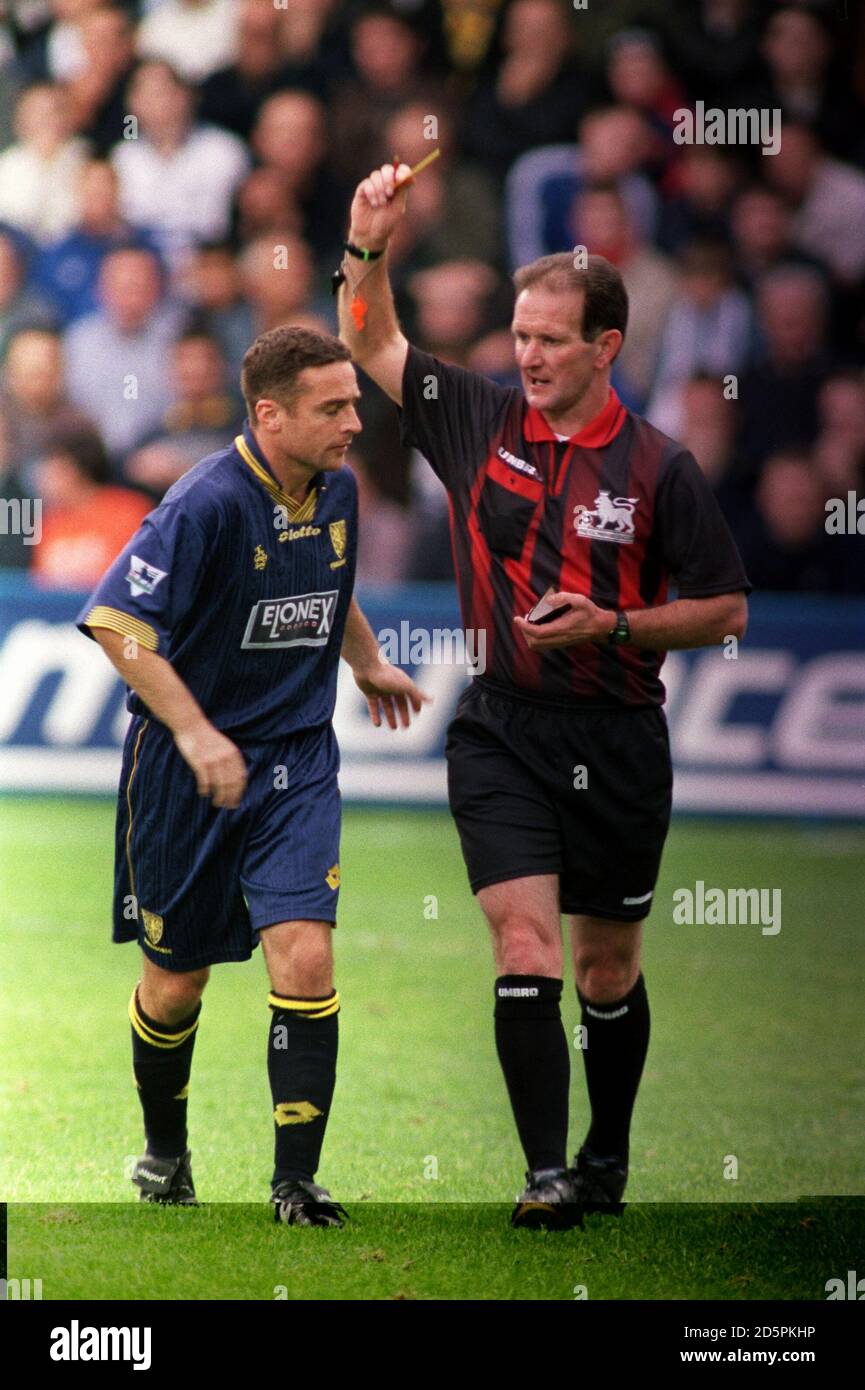 Referee Paul Alcock (right), taking charge of his first game since the incident with Paolo Di Canio, books Wimbledon's Michael Hughes (left) Stock Photo