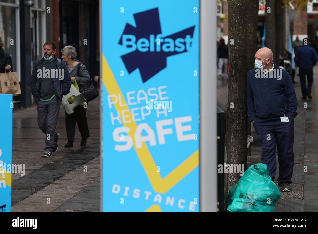A man wearing a face mask in Belfast city centre, Northern Ireland, after the Stormont executive announced closures of schools, pubs and restaurants as the region enters a period of intensified coronavirus restrictions in response to spiralling infection rates. Stock Photo