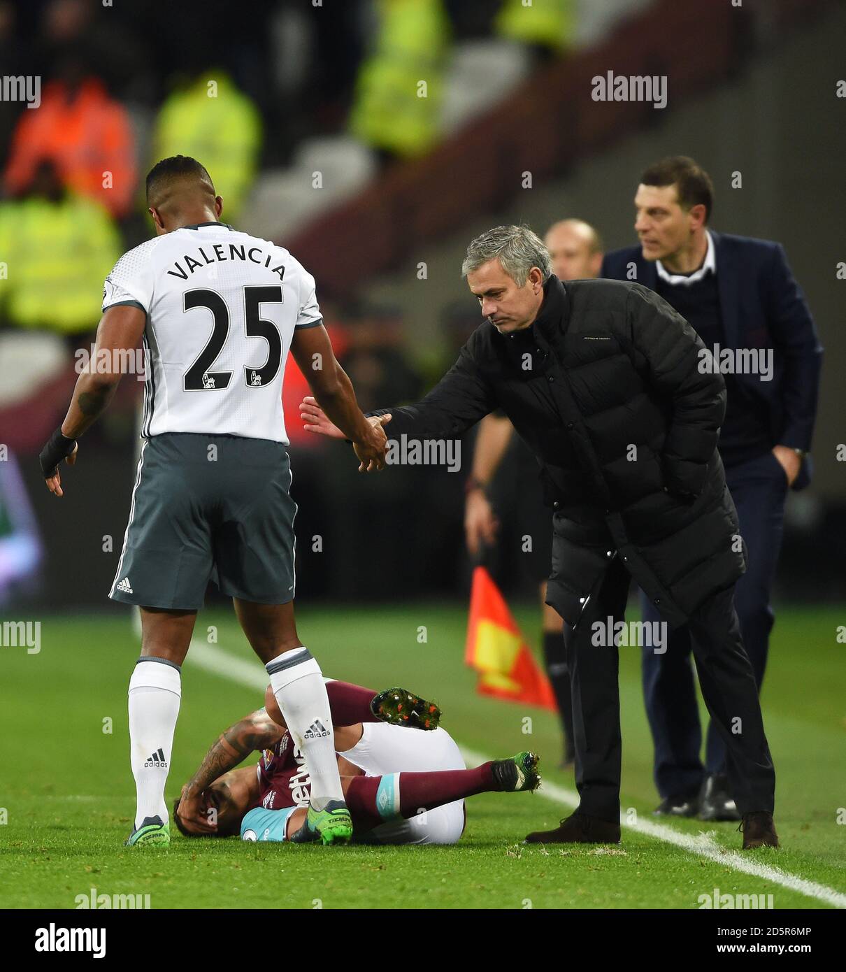 Manchester United's Luis Antonio Valencia (left) shakes hands with manager Jose Mourinho as West Ham United's Manuel Lanzini lies in pain Stock Photo