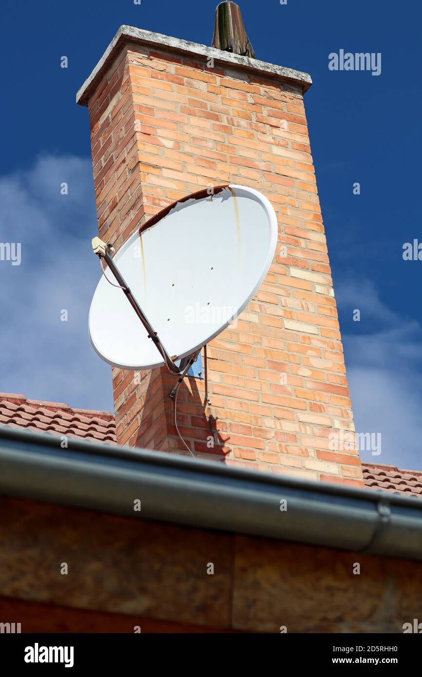 Roof with chimney and satellite dish. Corrosion on satellite. Sunny day