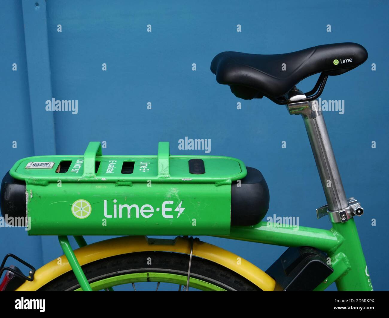 Close up and detail of a Lime electric bike seen against a blue background. Stock Photo
